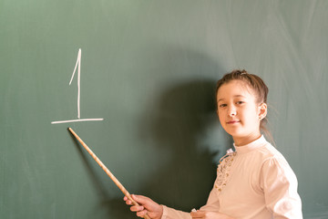 schoolgirl near the board with a pointer. A girl at school teaching figures