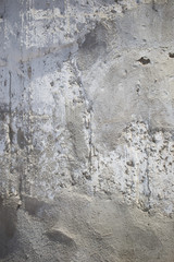 Texture of an old white concrete wall with small holes and a shadow