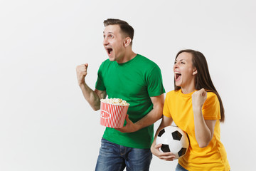 European young couple, woman, man, football fans in yellow green t-shirt cheer up support team with soccer ball bucket of popcorn isolated on white background. Sport, family leisure, lifestyle concept