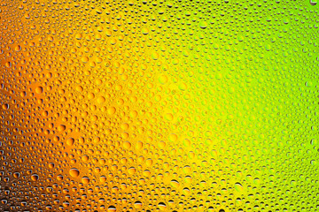 Close up of a water drops on a yellow,orange,green  and brown gradient background, covered with drops of water -condensation.