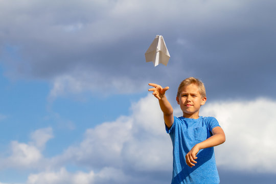 Boy throwing paper plane against blue sky