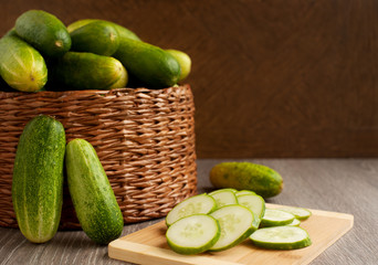 Harvest of cucumbers in a basket. Large wicker basket with cucumber on a wooden background. Vegetables on a cutting board.