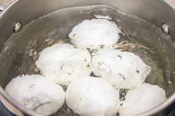 White chicken eggs boil in a saucepan