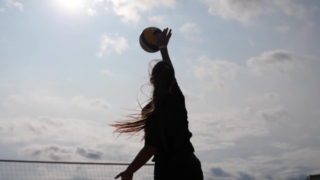 Girl silhouette play beach volleyball hit the ball in slow motion