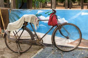 Fototapeta na wymiar old rusty bicycle covered with a towel is parked against a wall in the south of india