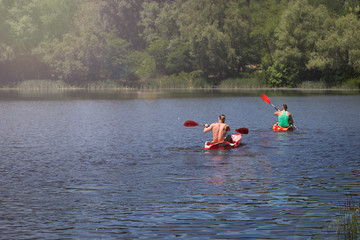 Young guys swim on kayaks along the river