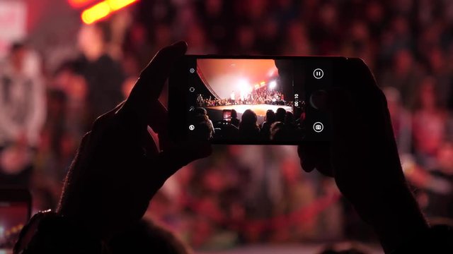 Holding shooting video or take picture on mobile smartphone camera during public event at night