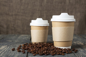 Two cup-thermos with hot drink, coffee beans on wooden table