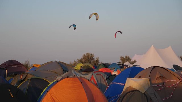 Camping tents near sea beach and kites flying high over them in air - Ukraine summer resort
