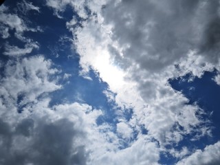 Fototapeta premium Beautiful White and Black Clouds on a Blue Sky with Sunlight in the Background