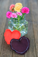 Plakat A heart pillows with flowers in vase on wooden table.