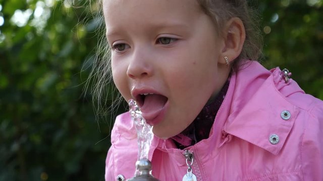 Little kid girl funny drink the water jet of drinking fountain walking in city center of Sofia Bulgaria