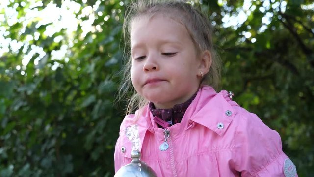 Little kid girl funny drink lapping the water jet of drinking fountain walking in city center of Sofia Bulgaria