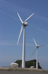 Two Huge white wind turbines against the sky