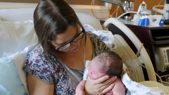A mother burping her newborn girl after nursing her in the hospital