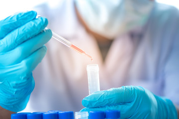 Pipette dropping a sample into a test tube, closeup