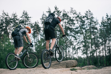 Fototapeta premium two male extreme cyclists in protective helmets riding on mountain bicycles in forest