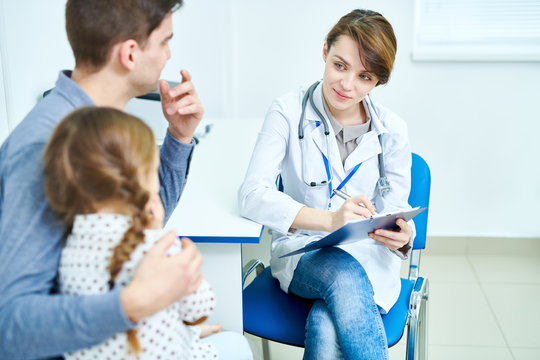 Crop view of female doctor sitting in office and listening to little patient