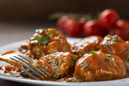 Meatballs with tomato sauce and fresh chopped parsley on plate with fork
