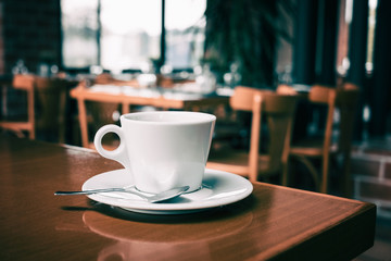 White coffee cup on wooden table in coffee shop blur background