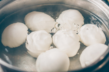 Fototapeta na wymiar Eggs in a white shell are boiled in boiling water in a saucepan