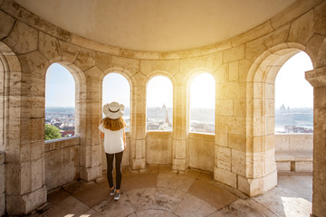 Young woman tourist enjoying cityscape view from the terrace with arches traveling in Budapest,...