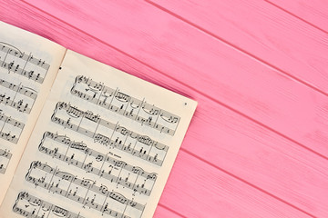 Sheet with musical notes, copy space. Paper with music notes on pink wooden table.
