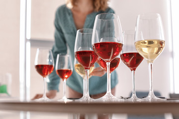 Glasses with delicious wine and blurred woman on background