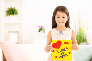 Little girl preparing greeting card for her mommy on Mother's Day at table