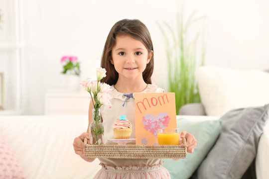 Little girl holding tray with breakfast and greeting card for her mommy on Mother's Day indoors