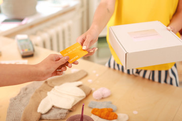Selling clothes. Young skillful needlewoman wearing stylish short striped shirts selling baby clothes for her regular client