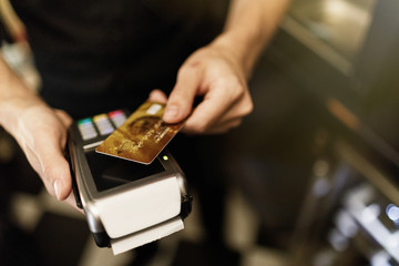 Hand of customer paying with contactless credit card with NFC technology.