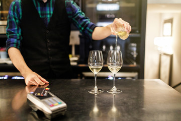 Pouring two glasses of white wine from a bottle in a close up view of the wineglasses