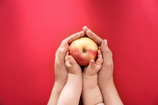 Young woman and little child holding apple on color background, top view. Healthy diet
