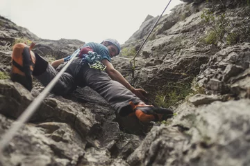 Foto auf Acrylglas Bergsteiger klettert auf einen Felsen © LStockStudio