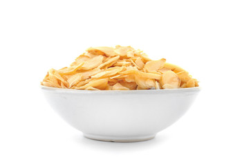 Dried garlic flakes in bowl on white background