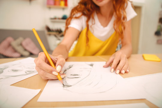 Female artist. Red-haired female artist feeling busy holding pencil in her hand while drawing nice portrait