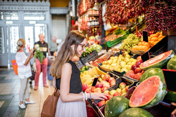 Young woman choosing goods standing at the counter with a bunch of different fresh food in theGreat...