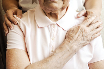 Mature female in elderly care facility gets help from hospital personnel nurse. Senior woman, aged...