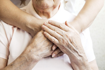 Mature female in elderly care facility gets help from hospital personnel nurse. Senior woman, aged...