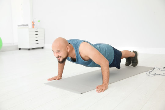 Overweight man doing exercise on floor in gym