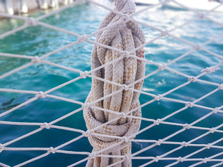 rope knot with blue sea behind fish net
