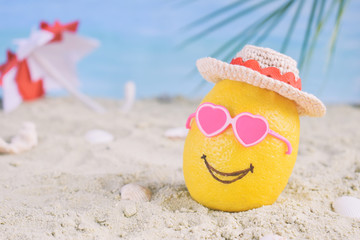 Creative minimal summer idea. Lemon citrus hipster in bamboo hat, sunglasses and beach umbrella on sand. Tropical beach concept. Creative art. Copy space