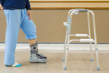 In the hospital, patients suffered from fracture of the ankle, needing to wear an orthopedic boot, and practice walking with Walker to maintain the balance. medical and orthopedic concept.