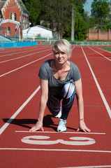 Obraz premium Sports woman fitness athlete at the start near the stadium, preparing for the sprint. Fitness, the concept of a healthy lifestyle