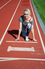 Obraz premium Sports woman fitness athlete at the start near the stadium, preparing for the sprint. Fitness, the concept of a healthy lifestyle