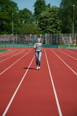 Sports woman running track and field running on a treadmill at the stadium on a sunny morning in the summer