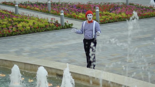 Mime in red beret has fun with fountains