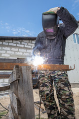 Welder welds metal at the construction site