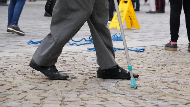Senior man legs walking with a stick on city center cobblestone